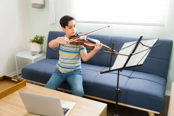 シートミュージックを読みながら弓でバイオリンを学ぶ可愛い小学生 才能のある子供が家で楽器を演奏する — ストック写真