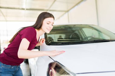 Mutlu ve işimle gurur duyuyorum. Kafkasyalı genç kadın gülümsüyor ve arabanın kaputu yıkandıktan sonra temiz mi diye kontrol ediyor.