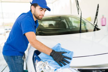 Araba yıkamada iyi görünümlü bir çalışan müşterinin arabasının farlarını temizliyor. Çalışkan genç adam bir arabayı yıkamayı bitiriyor. 