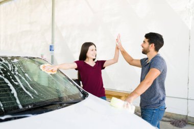 İyi bir takım olduk. Mutlu çift evlerinin önünde arabalarını yıkadıktan sonra gülüyor ve beşlik çakıyor.