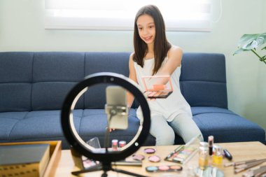 Makyaj ürünlerini gözden geçiriyorum. Makyaj videosu dersinde göz farı paleti kullanan sevimli bir kız. 