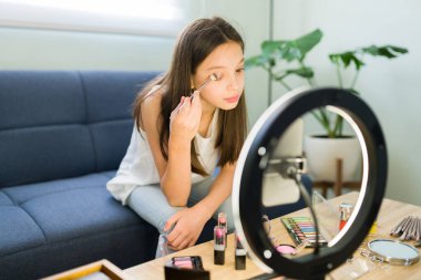 Makyaj dersimi takip et. Güzel, beyaz bir kız güzellik videosu çekerken göz farı sürüyor. 