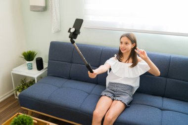 Nüfuzlu çocuk merhaba diyor ve takipçileri ve abonelerine barış işareti yapıyor. Moda blogcusu evde otururken selfie çubuğuyla fotoğraf çekiyor.