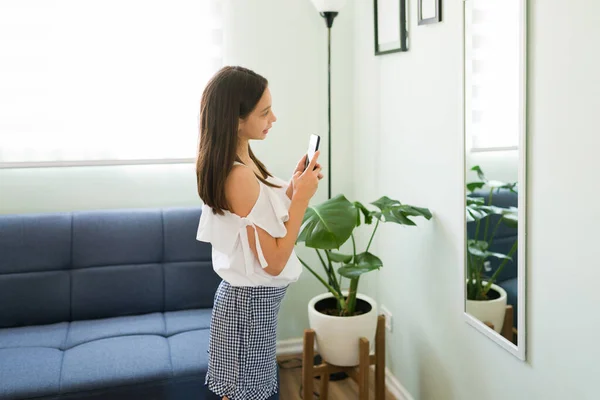 I\'m posting this picture on my social media. Caucasian young girl taking a mirror selfie at home before going out to hang out with her friends