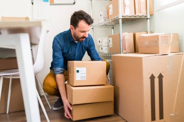 Birçok müşterinin siparişiyle başarılı bir iş. Çevrimiçi mağazası olan genç bir adam paketleri göndermek için hazırlıyor.