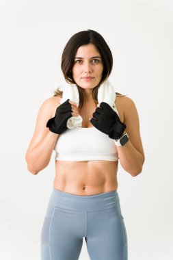 Spor salonunda harika sonuçlar aldım. Kaslı güçlü genç bir kadın spor salonunu bitiriyor ve terini havluyla temizliyor.