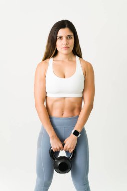 Mazeret yok. Güzel, güçlü bir kadının portresi. Karın kasları kaslı. Kettlebell ağırlığı tutuyor ve vücut çalışırken göz teması kuruyor. 