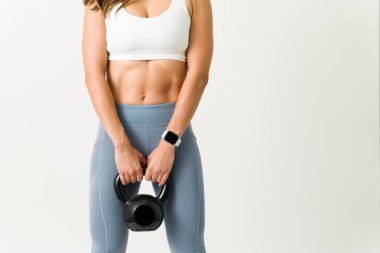 Spor salonuna gitmek için güçlü bir motivasyon. Güçlü karın kasları ve vücut kasları olan, kettlebell ağırlığı taşıyan atletik bir kadını yakından çek.