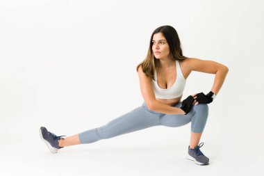 Eğitimime başlamak için ısınıyorum. Sportif kadın ağırlık çalışmadan önce bacaklarını esnetiyor.