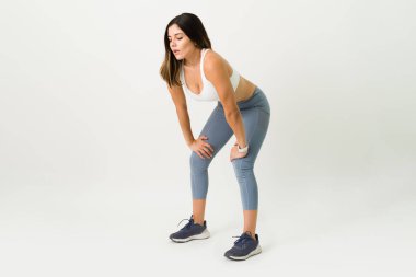 Güçlü bir egzersizden sonra soluklanıyorum. Spor kıyafetlerinde yorgun genç bir kadın egzersiz yaptıktan sonra bitkin düşüyor.