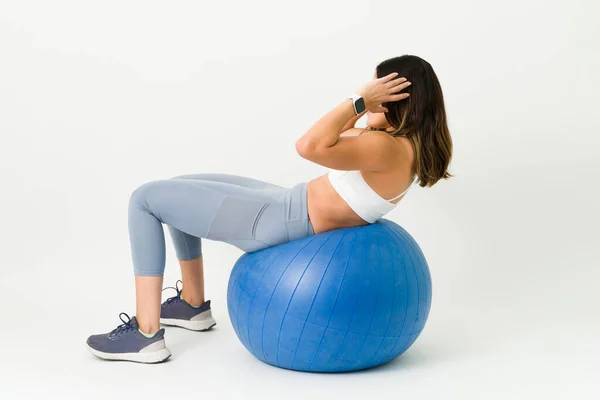瘦小的年轻女子 体态丰满 躺在健身球上做腹肌挤压 适合使用稳定球进行运动的女人 — 图库照片