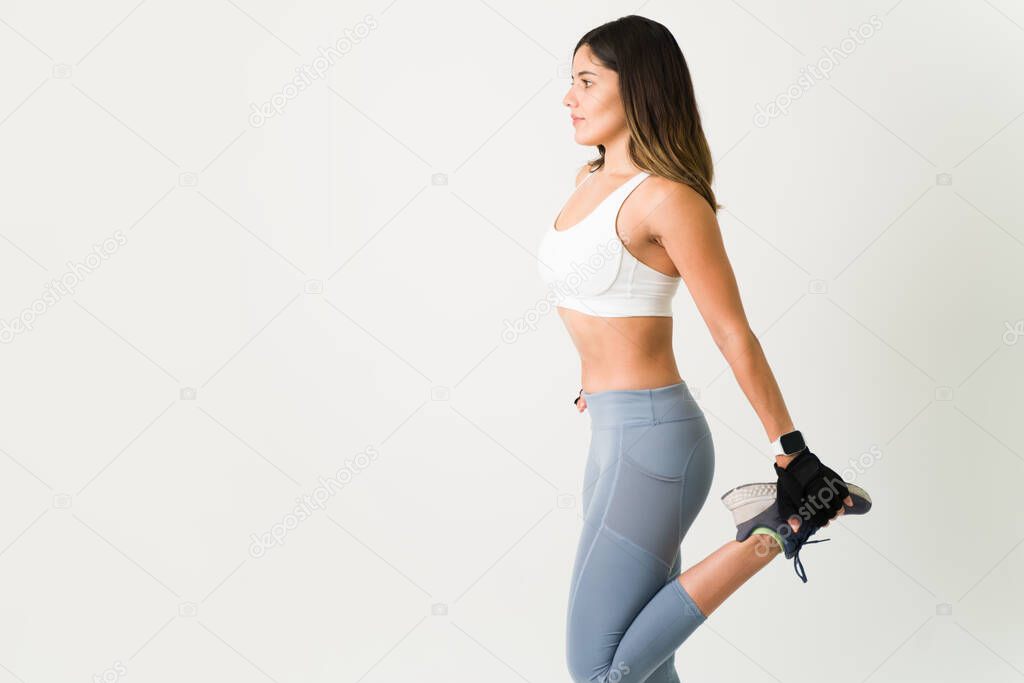 Stretching is important before a workout routine. Female slim athlete doing warmup exercises to start her cardio routine at the gym 