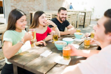 Eğlenceli arkadaşlar açık hava barında gülüp abur cubur yiyorlar. Üniversite arkadaşları şaka yapıyor ve içkilerle takılıyor.