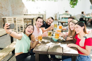 Bu anı hatırlamak için selfie. Bir barda takılıp bira içerken akıllı bir telefonla fotoğraf çeken heyecanlı üniversite arkadaşları.