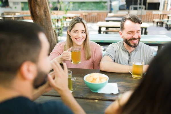 屋外のバーで友人と素敵な会話をしている美しい白人の若い女性 ビールを飲みながら笑う友達 — ストック写真