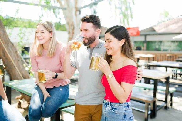 屋外バーで友人とビールを飲みながら 抱き合って笑っているカップル 彼氏と彼女は友人のグループと付き合って — ストック写真