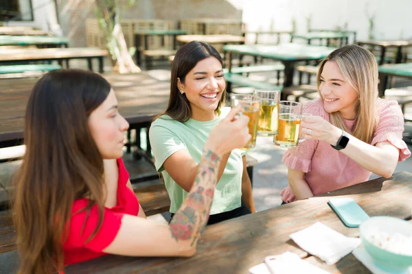 親友よ 冷たいビールと笑いで乾杯する幸せな若い女性 バーで一緒に午後を過ごす美しいビーティー — ストック写真
