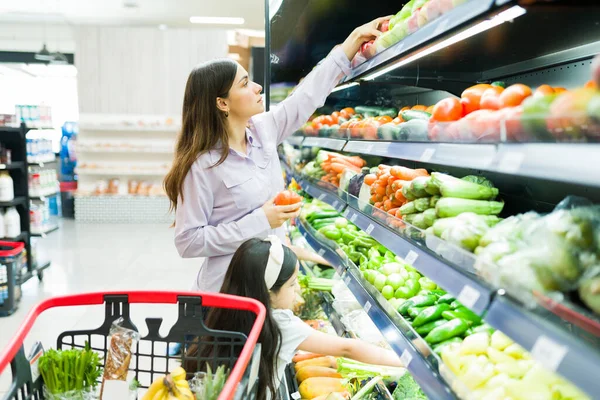 ヒスパニック系の母親は子供と一緒に店で野菜や果物を買っています スーパーで健康的な新鮮な製品を選択する美しい女性 — ストック写真