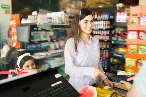 女性のお客様はスーパーでクレジットカードで笑顔と支払います グッドルッキング女性と子供でザ チェックアウトカウンター購入食品 — ストック写真
