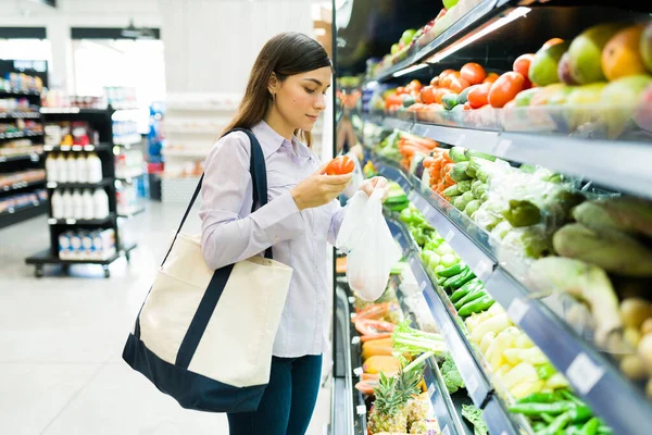 生鮮食品を買う スーパーの通路の横に立って 食料品店で袋に野菜を入れて美しい女性 — ストック写真