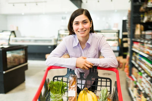 Vrolijke Vrouw Die Voedselproducten Haar Kar Legt Tijdens Het Lopen — Stockfoto