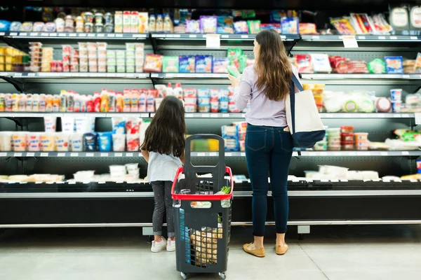 Rear view of a latin family looking and choosing dairy products at the supermarket during a quick shopping trip to the store