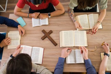 Toplantida bir grup gencin incili birlikte okumasi ve kutsal yazilari Katolik haçlarinin etrafinda incelemesi.