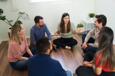 20 'li yaşlarda üzgün bir kadın terapi grubunda oturuyor. AA üyelerine tavsiye ve destek isteyen genç bir kadın 