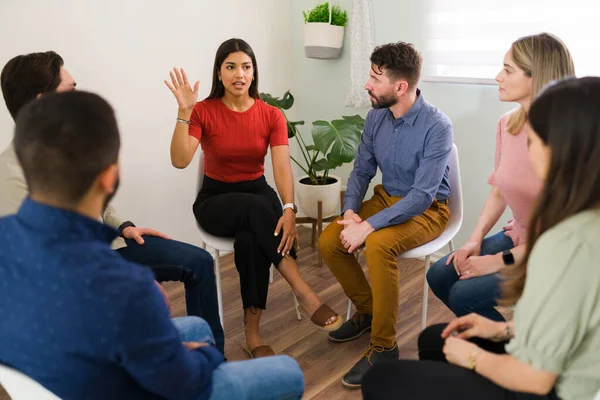 I want to share my experience. Attractive young woman raising her hand and asking to speak at a counseling group