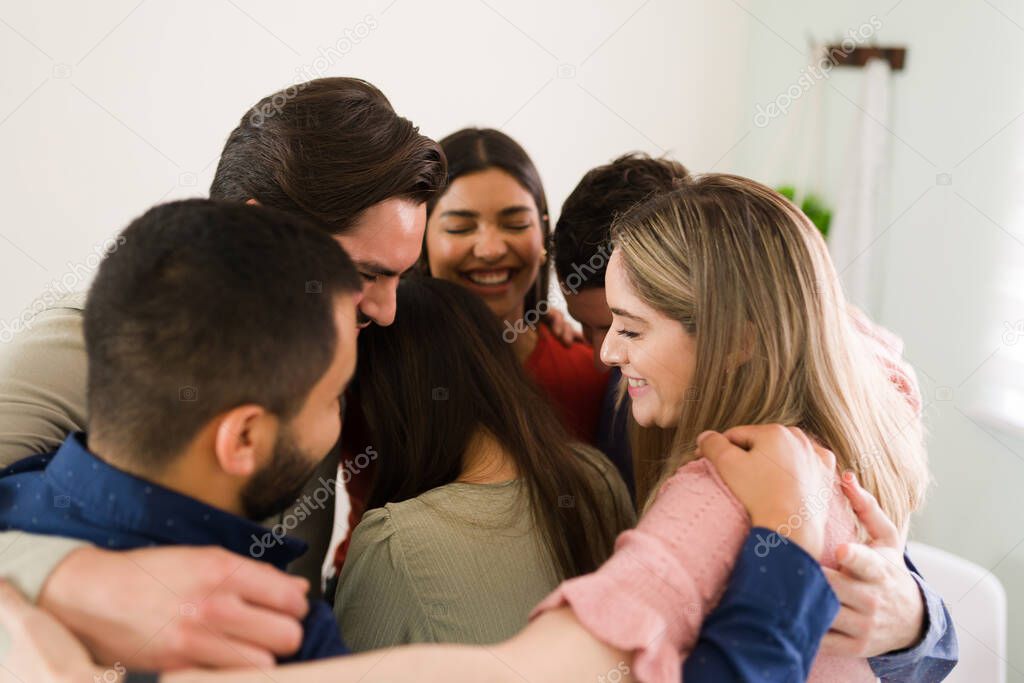 Together we are stronger. Happy group of diverse people hugging a young woman. Members of a rehab center giving love and support 