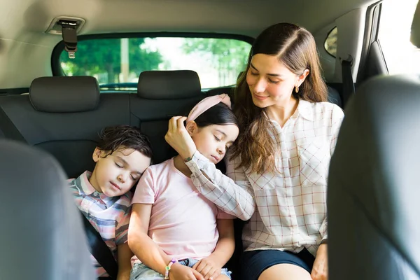 累了的小孩在外面玩了一整天后和妈妈在车里睡着了 有爱心的年轻女人和妈妈爱抚着女儿的脸 — 图库照片