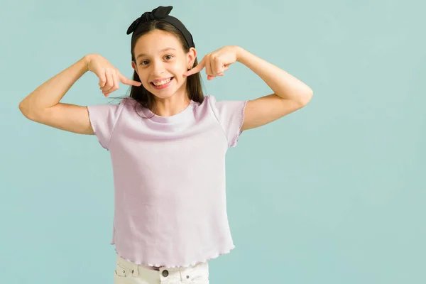 君の顔に笑顔を 愛らしいですPreteen女の子とともにピンクTシャツ指しています彼女のBeaming笑顔とあなたに正の滞在を求める — ストック写真