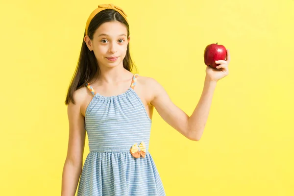 白人の少女は健康的な軽食として赤いリンゴを食べています 幸せな若いです女の子保持しながら果物を作ります目の接触で明るい背景 — ストック写真
