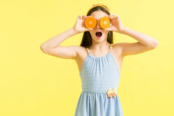 驚くべき若いです女の子見ます何か素晴らしいです一方 持っているスライスのオレンジ果実で彼女の目 — ストック写真
