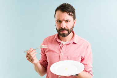 30 'lu yaşlarda sağlıksız bir adam yemek yeme bozuklukları yüzünden elinde çatal ve tabak tutuyordu.