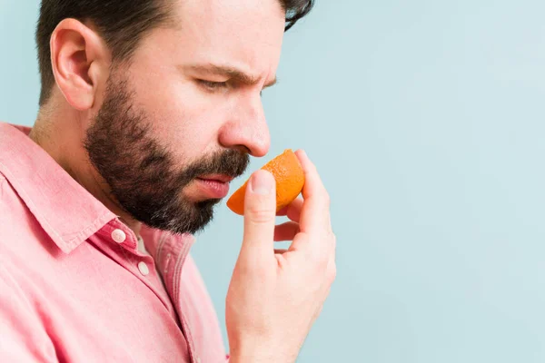 Smutny Młodzieniec Trzymający Pomarańczowy Owoc Przed Nosem Próbujący Powąchać Latynos — Zdjęcie stockowe