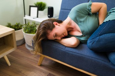 Apandisitten muzdarip genç bir kadın ve oturma odasında tek başına yatarken midesinde çok fazla ağrı var.