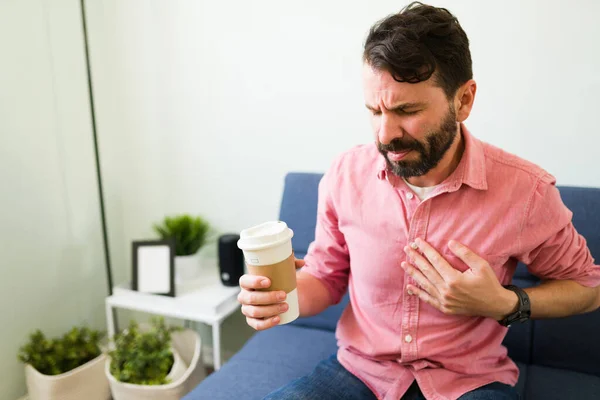 咖啡因的不良反应 紧张的男人摸着胸口 喝了一杯咖啡后就得了心动过速 — 图库照片