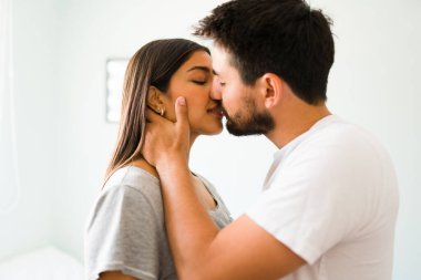 Yatmadan önce güzel bir kadın ve rahat pijama giyen Latin bir adamın şehvetli bir öpüşme profili.