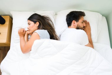 Top view of an attractive couple turning their backs and feeling angry with each other after having a fight before sleep