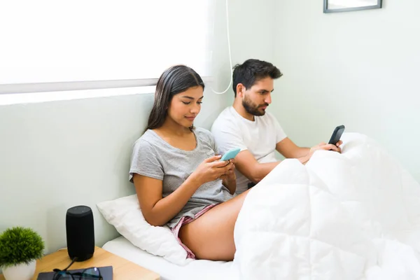 Glad Flickvän Och Pojkvän Pyjamas Använder Sina Smartphones Sängen Latin — Stockfoto