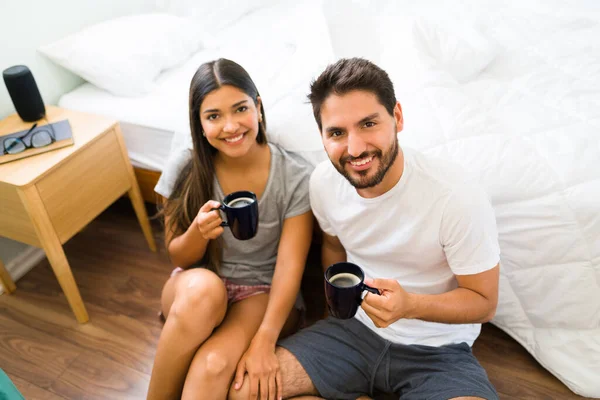 享受早晨的悠闲时光 穿着睡衣的年轻貌美的情侣们一边在卧室里喝杯热咖啡 一边微笑着 眼神交流 — 图库照片