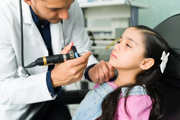 由于鼻窦炎 在耳鼻喉科医生那里是个可爱的小女生 儿科医生用腹腔镜检查一个小病人的鼻子 — 图库照片