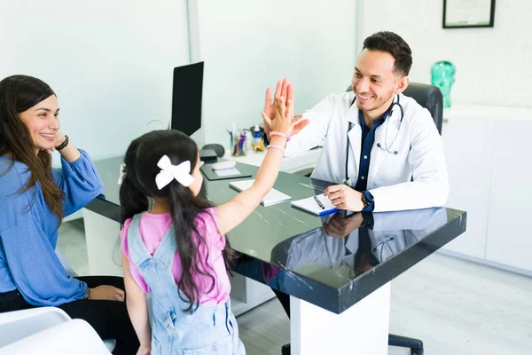 开开心心的拉丁医生在他的办公室里给了一个小女孩一个5分的高分 男儿科医生向一位小病人和他微笑的妈妈问好 — 图库照片