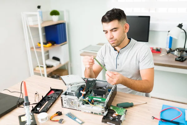 Young engineer checking the RAM memory of a computer at work. Attractive man in his 20s fixing a CPU in the repair shop