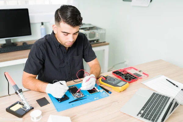 Engenheiro Masculino Hispânico Verificando Conexões Smartphone Danificado Com Multímetro Sua — Fotografia de Stock