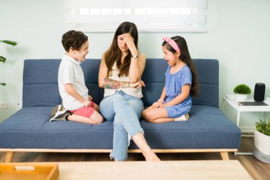 Ne yapacagimi bilmiyorum. Yorgun genç bir anne, çocuklarının evde bağırıp kavga etmelerini engellemeye çalışırken yorgun hissediyor.