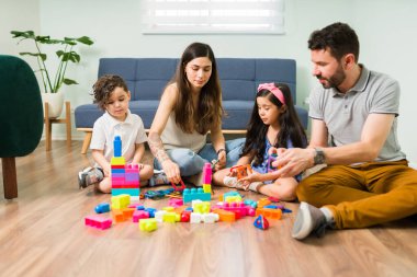 Hep birlikte oynuyoruz. Renkli mıknatıslarla oynayan ve evlerinin zemininde yapı taşlarıyla oynayan dört kişilik eğlenceli bir aile.