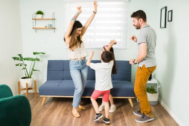 Tatlı çocukları ve kocasıyla dans ederken gülen neşeli ve çekici bir anne. Dört kişilik güzel bir aile müzik dinliyor ve çalıyor. 