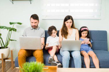 Dört kişilik güzel bir aile kanepede oturup dizüstü bilgisayarda yazı yazıyor. Anne, baba ve çocuklar boş günlerinde kendilerini eğlendiriyorlar. 